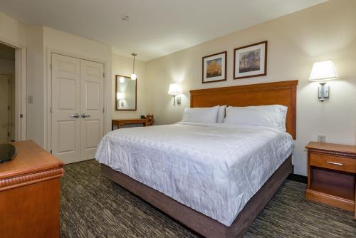 a hotel room with a large bed with white sheets at Candlewood Suites Mobile-Downtown by IHG in Mobile