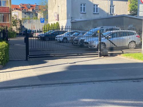 a fence with cars parked in a parking lot at Apartament Dwupoziomowy - klimatyzacja in Słupsk