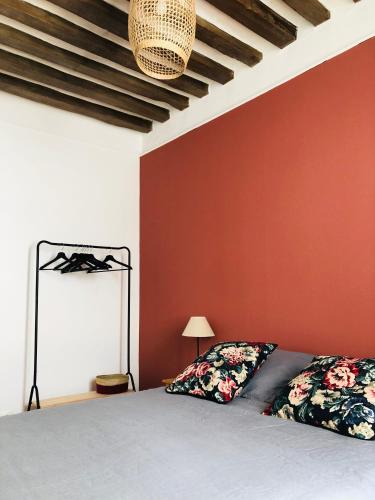 1 dormitorio con cama y pared roja en L’Apparté, en La Roche-Guyon