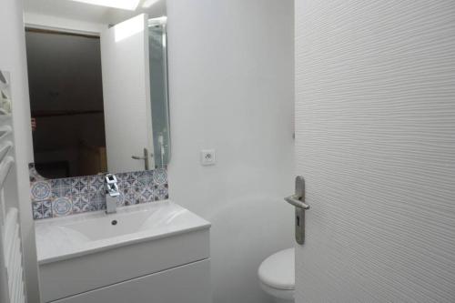 a bathroom with a sink and a mirror and a toilet at Maisonnette climatisée avec parking privé in Montfort