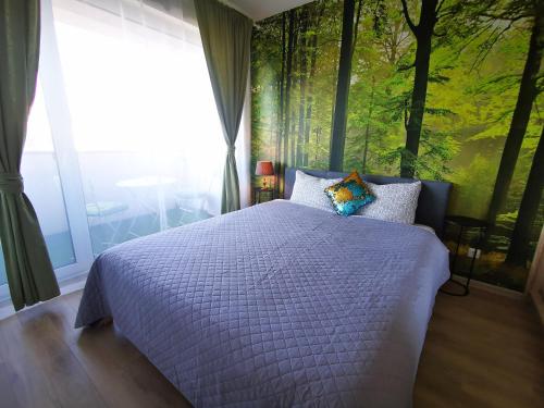 a bedroom with a bed with a forest mural on the wall at Bučiukas in Palanga