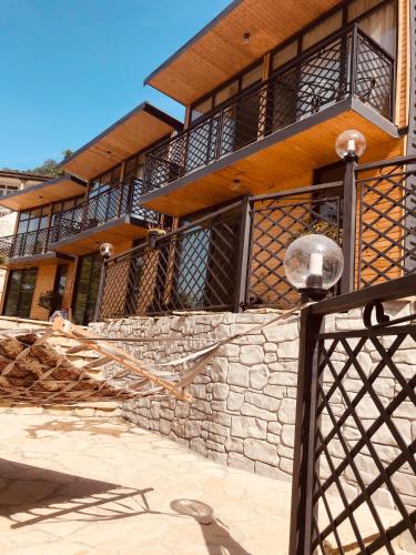 a building with a stone wall and a fence at Chalet Kvariati in Kvariat'i