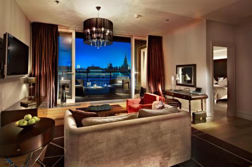 a living room with a couch and a large window at The Grand Mark Prague - The Leading Hotels of the World in Prague