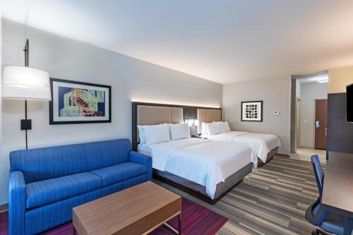 a hotel room with two beds and a blue couch at Holiday Inn Express & Suites Purcell, an IHG Hotel in Purcell