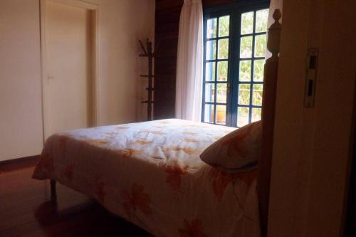 a bedroom with a bed and a window at casinha linda campos do jordão in Campos do Jordão