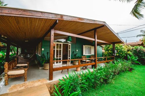 a green house with a wooden roof at Pousada Verdes Mares in Fernando de Noronha