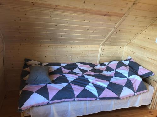 a bed in a room with a wooden wall at Roztoczańskie Chatki in Kaczórki