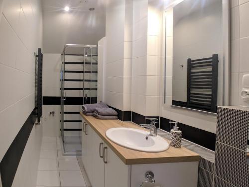 La salle de bains blanche est pourvue d'un lavabo et d'un miroir. dans l'établissement HOSTE Apartamenty na wczasy, à Chmielno