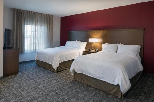 a hotel room with two beds and a flat screen tv at Staybridge Suites - Phoenix – Biltmore Area by IHG in Phoenix