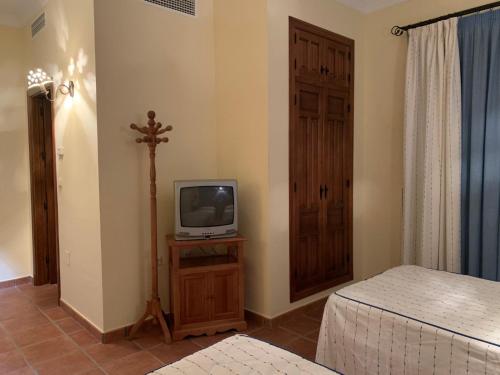 a bedroom with a tv on a dresser with a bed at Habitaciones rurales Venta Pedro in Casabermeja