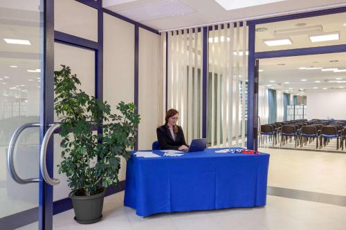 a woman sitting at a blue table with a laptop at Best Western Blu Hotel Roma in Rome