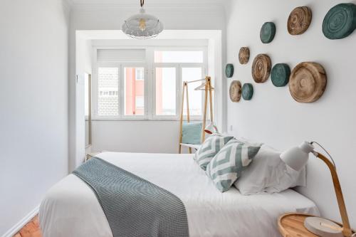a bedroom with a bed and plates on the wall at Stroll to Coffee Shops Near a Renovated Hillside Apartment in Graça in Lisbon