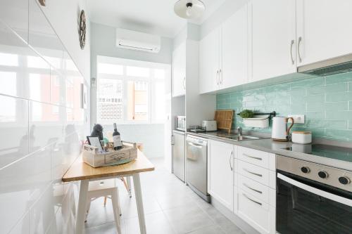 a kitchen with white cabinets and a wooden table at Panoramic River View 1-BR near Senhora do Monte by NestAtLisbon in Lisbon