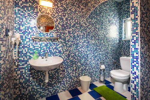 a bathroom with a sink and a toilet with blue tiles at Penzion Kozí farma Nový Dvůr in Česká Lípa