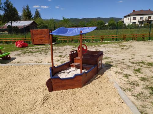 a playground in the sand with an umbrella at Apartamenty przy Jeziorze Żywieckim z widokiem na Skrzyczne in Żywiec