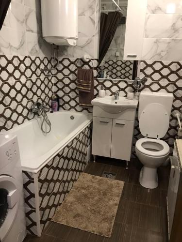 a bathroom with a toilet and a tub and a sink at Apartman Panorama in Vukovar