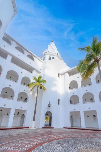 a white building with palm trees in front of it at Las Hadas by Brisas in Manzanillo