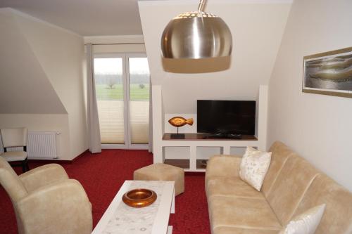 a living room with a couch and a tv at Ostseehotel Boltenhagen in Boltenhagen