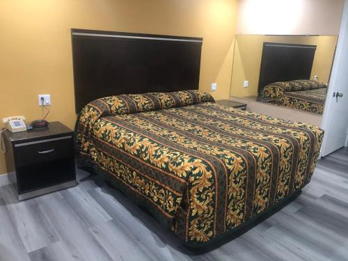 a hotel room with a bed with a blanket on it at Economy Inn - Ontario Airport in Ontario
