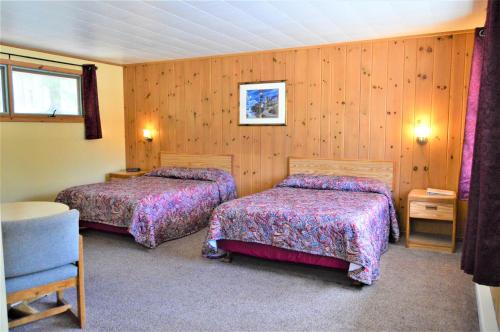 two beds in a room with wooden walls at Baileys Sunset Motel in Baileys Harbor