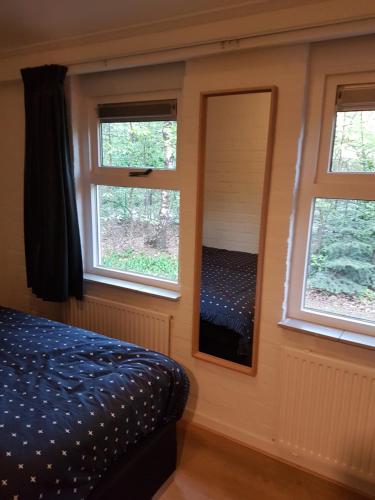 a bedroom with a bed and two windows at Bospark De Schaapskooi in Epe