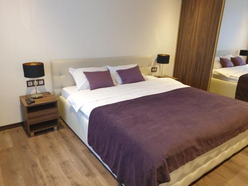 ein Schlafzimmer mit einem großen Bett und einem Nachttisch in der Unterkunft MARBEO 5 star luxury suites - Elkonu in Liepāja