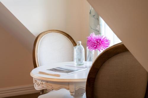 a small table with a bottle and a flower on it at French Bay House in Akaroa