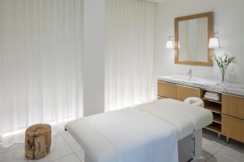 a white bedroom with a bed and a mirror at Lotte Hotel Seattle in Seattle