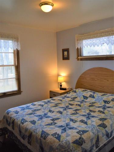 a bedroom with a bed with a blue and white quilt at Baileys Sunset Cottages in Baileys Harbor