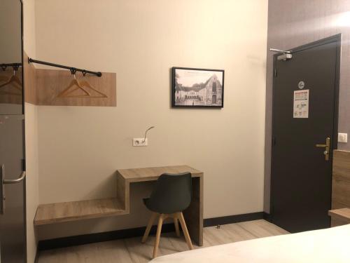 a room with a desk and a chair next to a door at LOGIS - Hôtel & Restaurant Saint Nicolas in Chaumont-en-Vexin