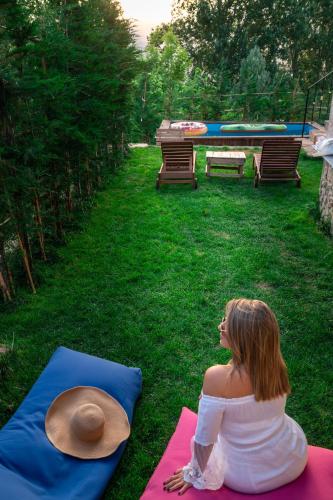 a woman sitting on a yoga mat in the grass at Austria Luxury Apartments, Faraya Hotel in Fārayyā