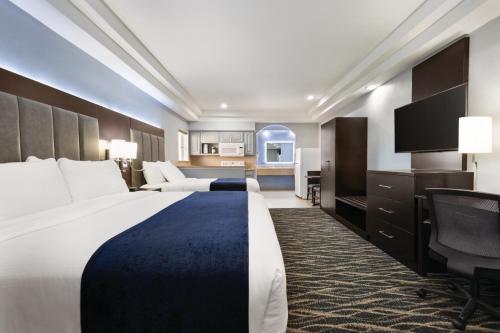 a hotel room with two beds and a desk at Days Inn & Suites by Wyndham Houston Hobby Airport in Houston