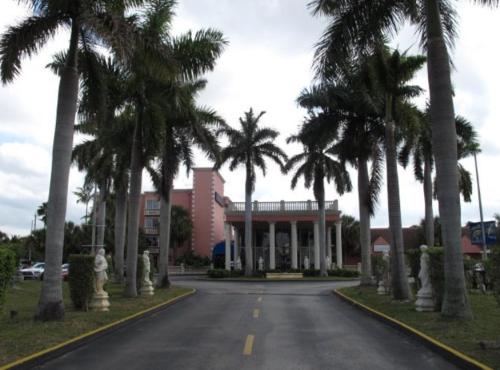 a street with palm trees in front of a building at Miami Gardens Inn & Suites in Miami