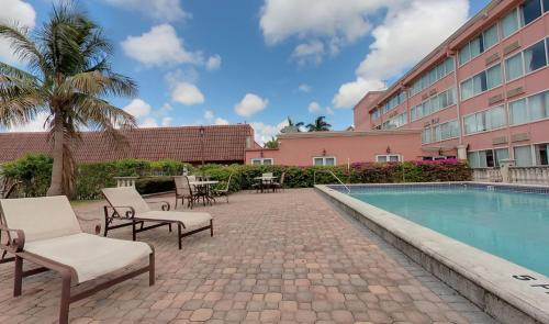
a patio area with a pool, chairs, and tables at Miami Gardens Inn & Suites in Miami
