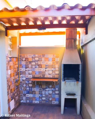 a pizza oven in a building with tiles on the wall at Kitnet Maitinga in Bertioga