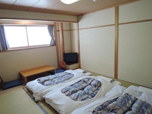 a room with two beds and a television in it at Maruni Ryokan in Hakuba