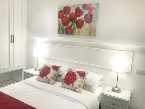 a white bedroom with a bed with red flowers on it at Dergvale Hotel in Dublin