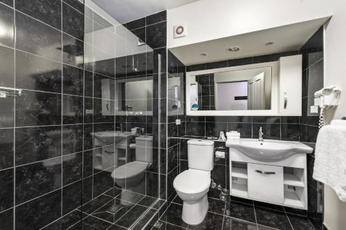 a black and white bathroom with a toilet and a sink at Quality Hotel Colonial Launceston in Launceston