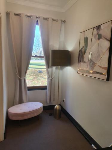 a room with a window with a bench and a lamp at The Lancefield Lodge in Lancefield