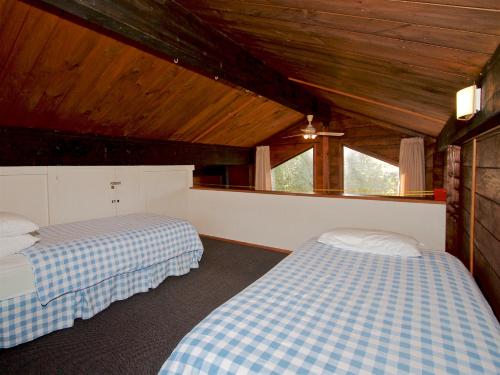 two beds in a room with wooden ceilings at The Cosy House - Ohakune Holiday Home in Ohakune