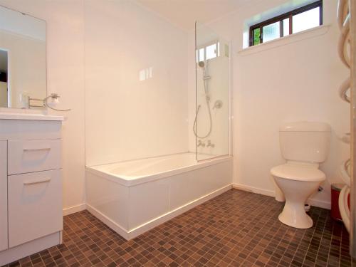 a white bathroom with a toilet and a shower at The Cosy House - Ohakune Holiday Home in Ohakune