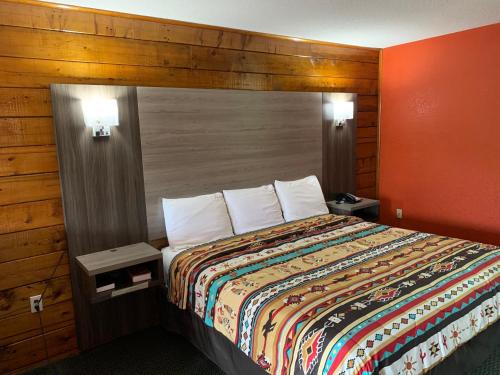 Habitación de hotel con cama con pared de madera en Log Cabin Inn en Bay Minette