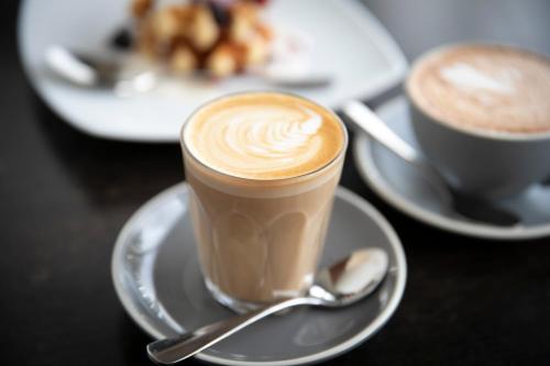 a cup of coffee on a plate with a spoon at ibis Sydney Airport in Sydney
