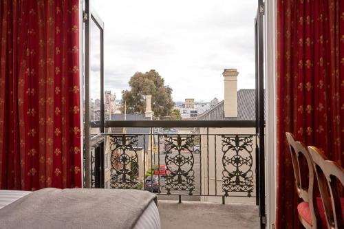 a balcony with a bed and a view of a city at Quality Hotel Colonial Launceston in Launceston