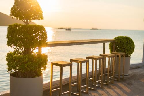 a row of stools sitting next to the water at Baan Tah On The Sea in Bang Sare