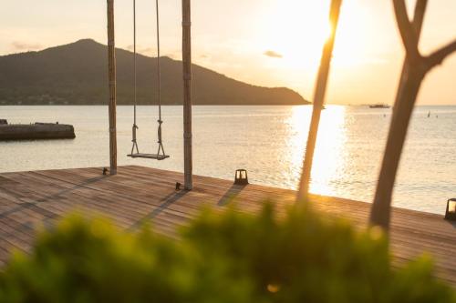 a dock with swings in front of a body of water at Baan Tah On The Sea in Bang Sare