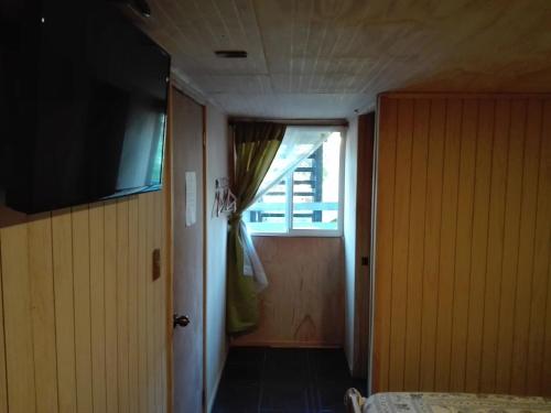 a room with a door and a window and a television at Hospedaje Los Calafates in Ancud