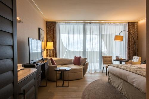 a hotel room with a couch and a television at AlpenGold Hotel Davos in Davos