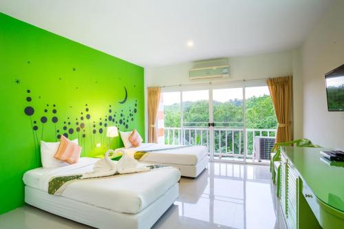 two beds in a room with a green wall at Phukaew Resort & Adventure Park in Khao Kho