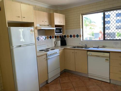 a kitchen with white cabinets and white appliances at Harbour Side Resort in Gold Coast